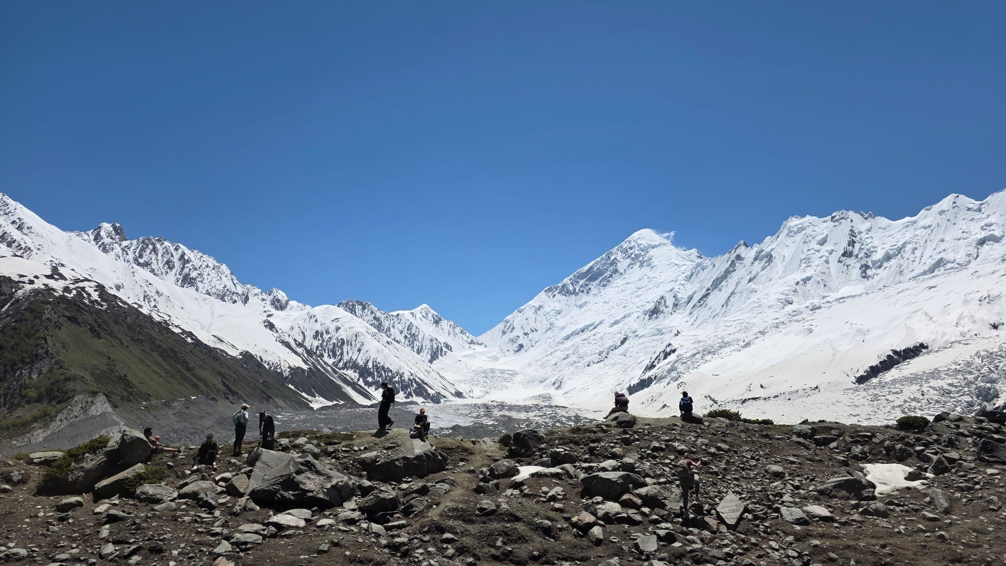 Trekkers beneath a vast snow-covered mountain